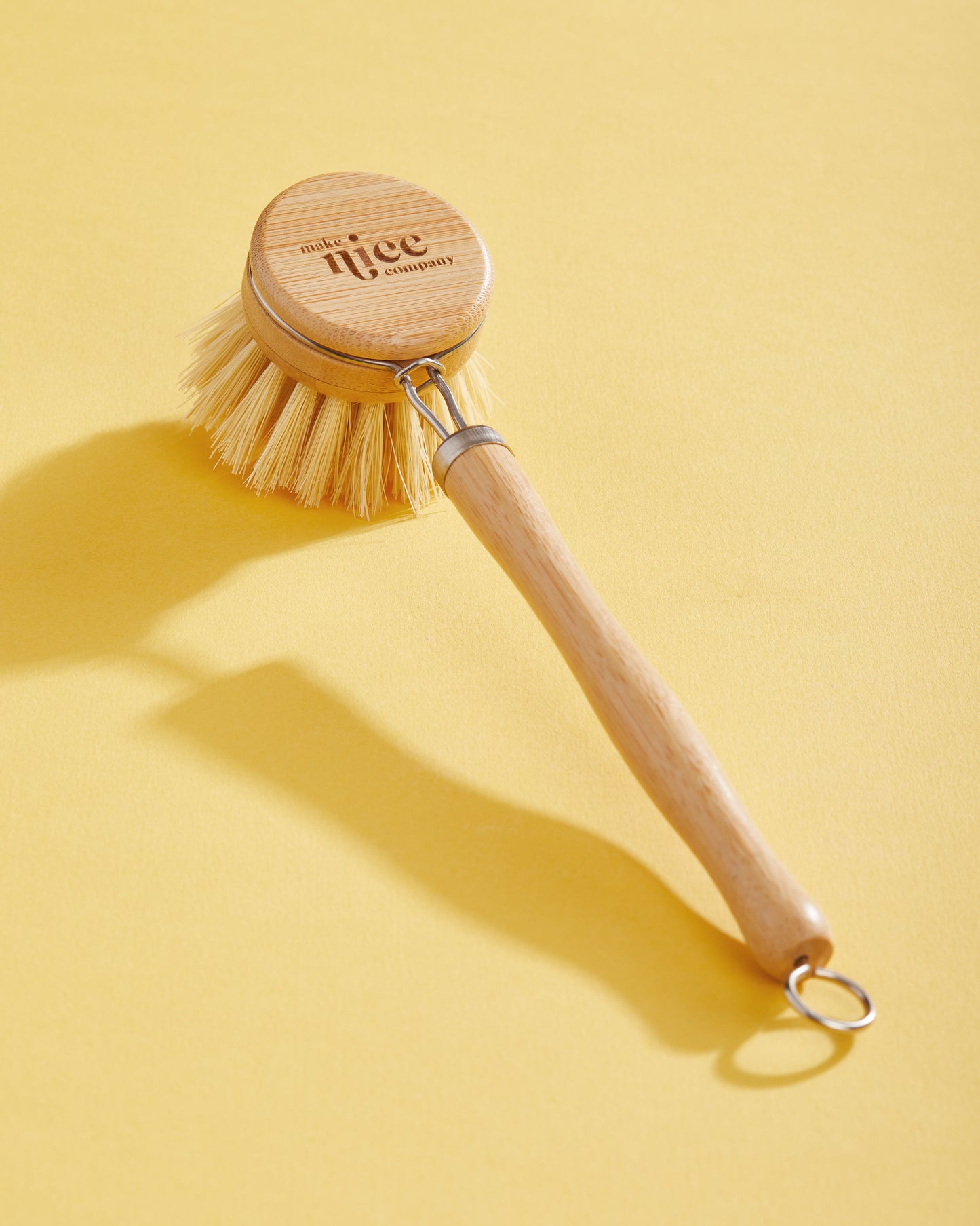 Make Nice Company eco-friendly Dish Brush on yellow background.
