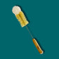 Cleaning brush with a wooden handle on a teal background